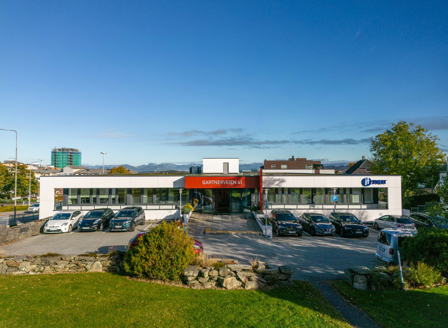 Hvitt avlangt lavt bygg fasadebilde med mye blå himmel