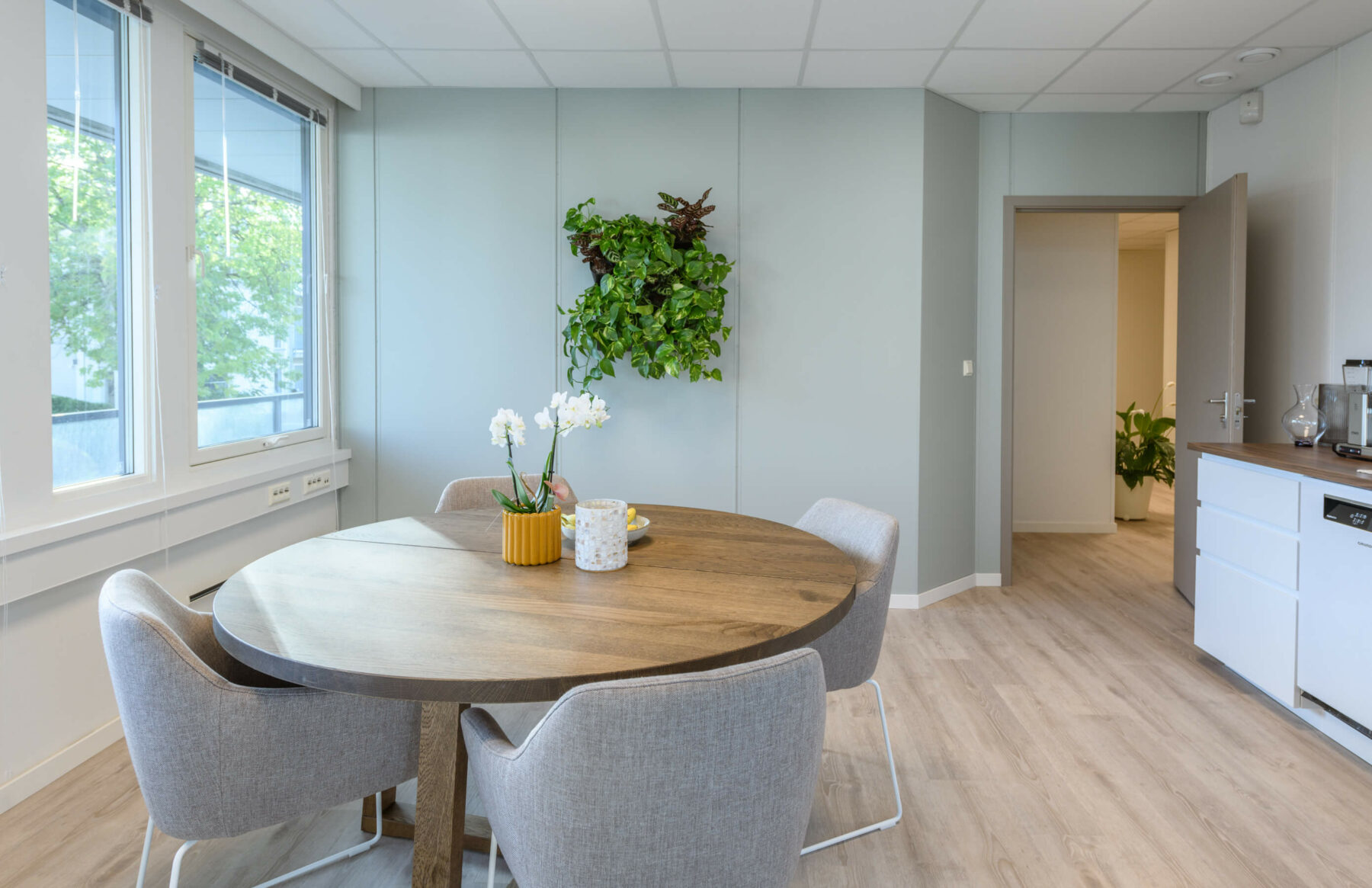 Rundt spisebord i tre med 4 stoler og kjøkken langs vegg