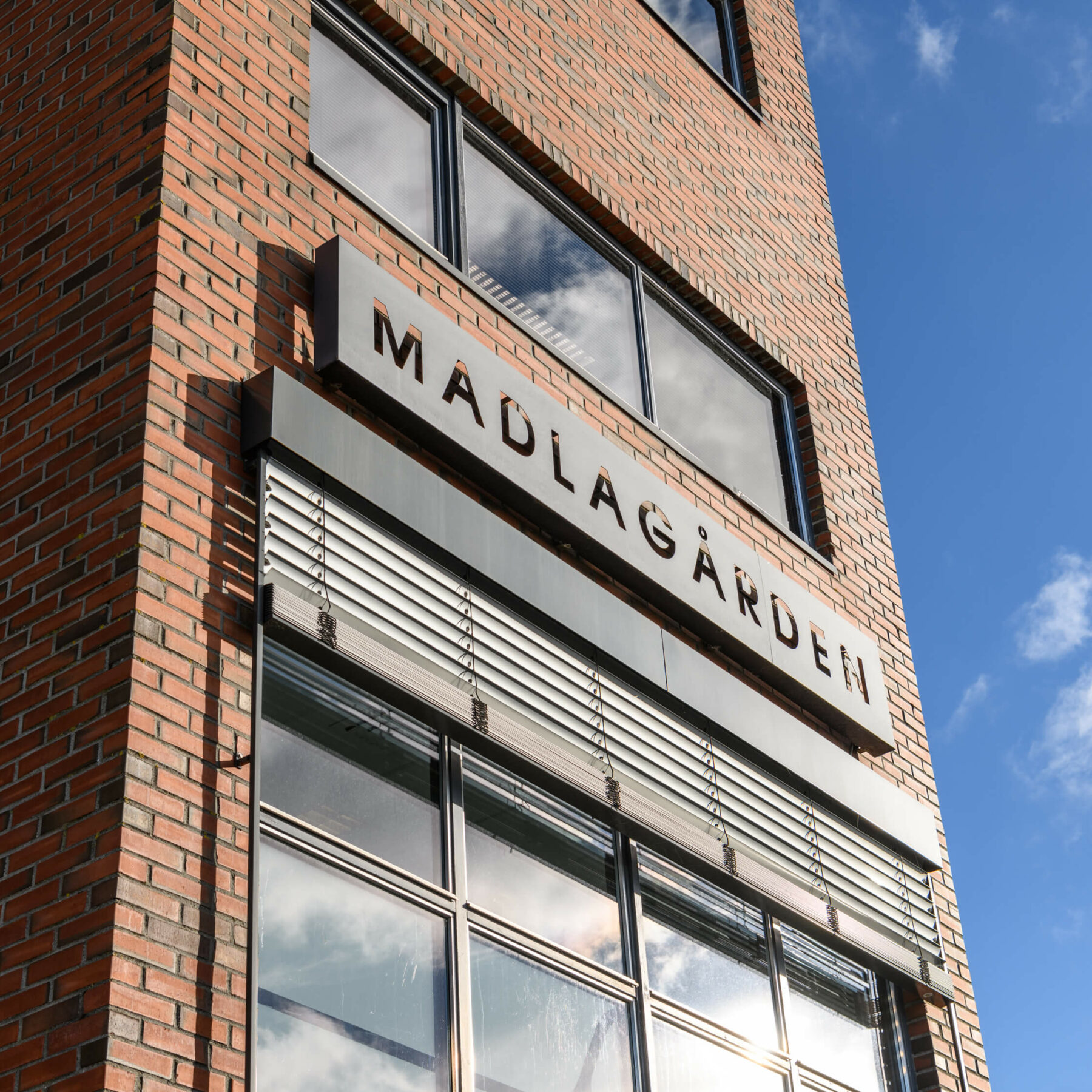 Murbygg med skilt i metall hvor det står Madlagården